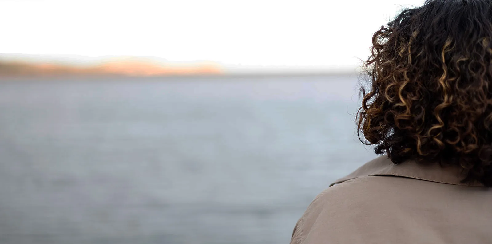 Girl looking off to the left with water behind